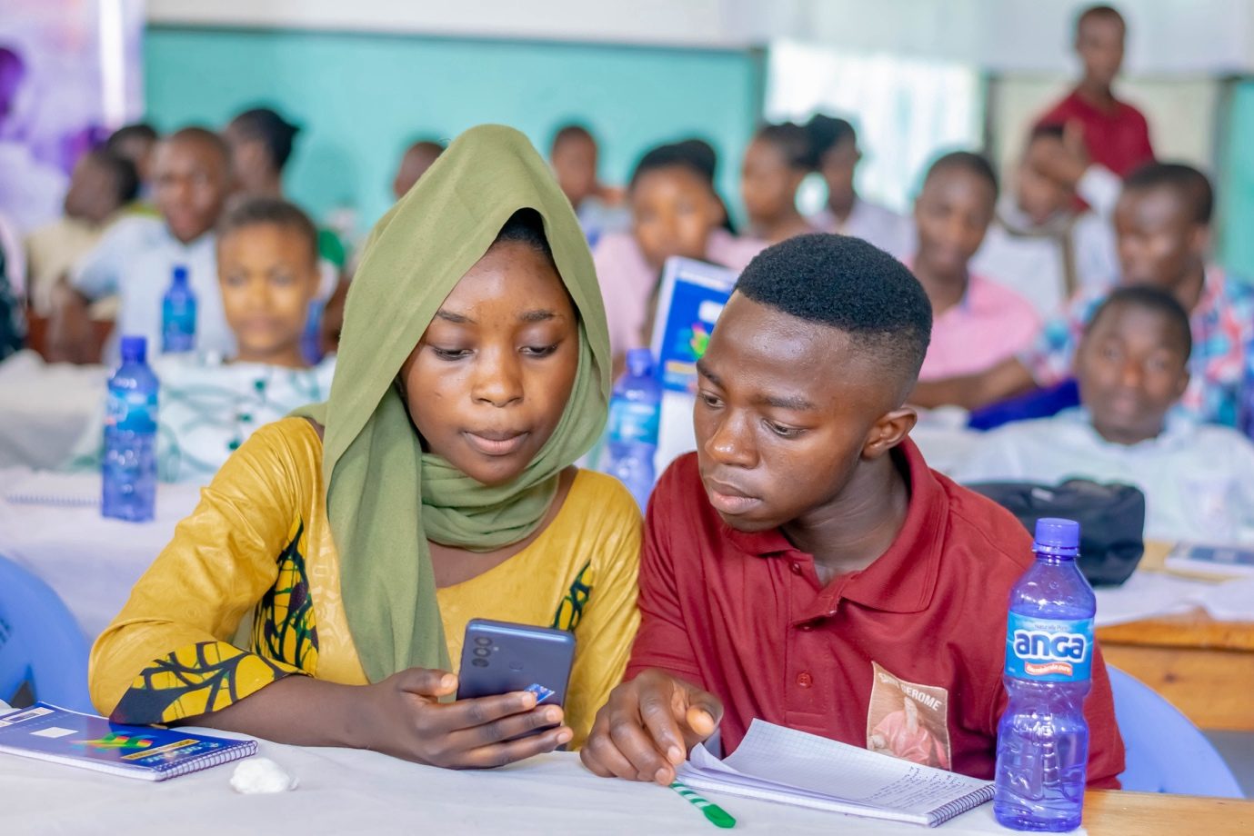Two Integrity Club members looking at a phone during a workshop in Bukavu